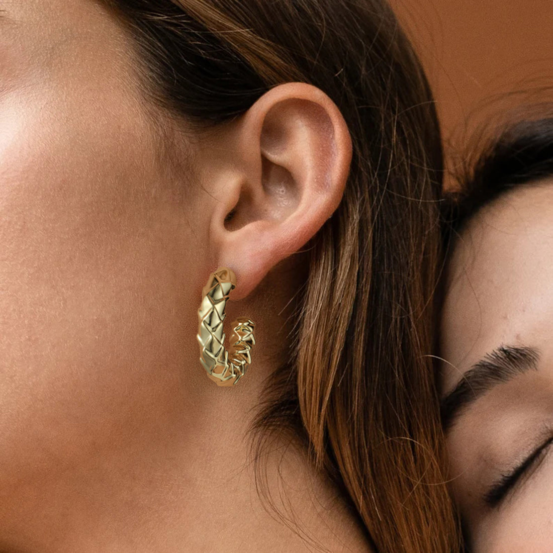 Golden-colored earrings with C-shaped diamond pattern