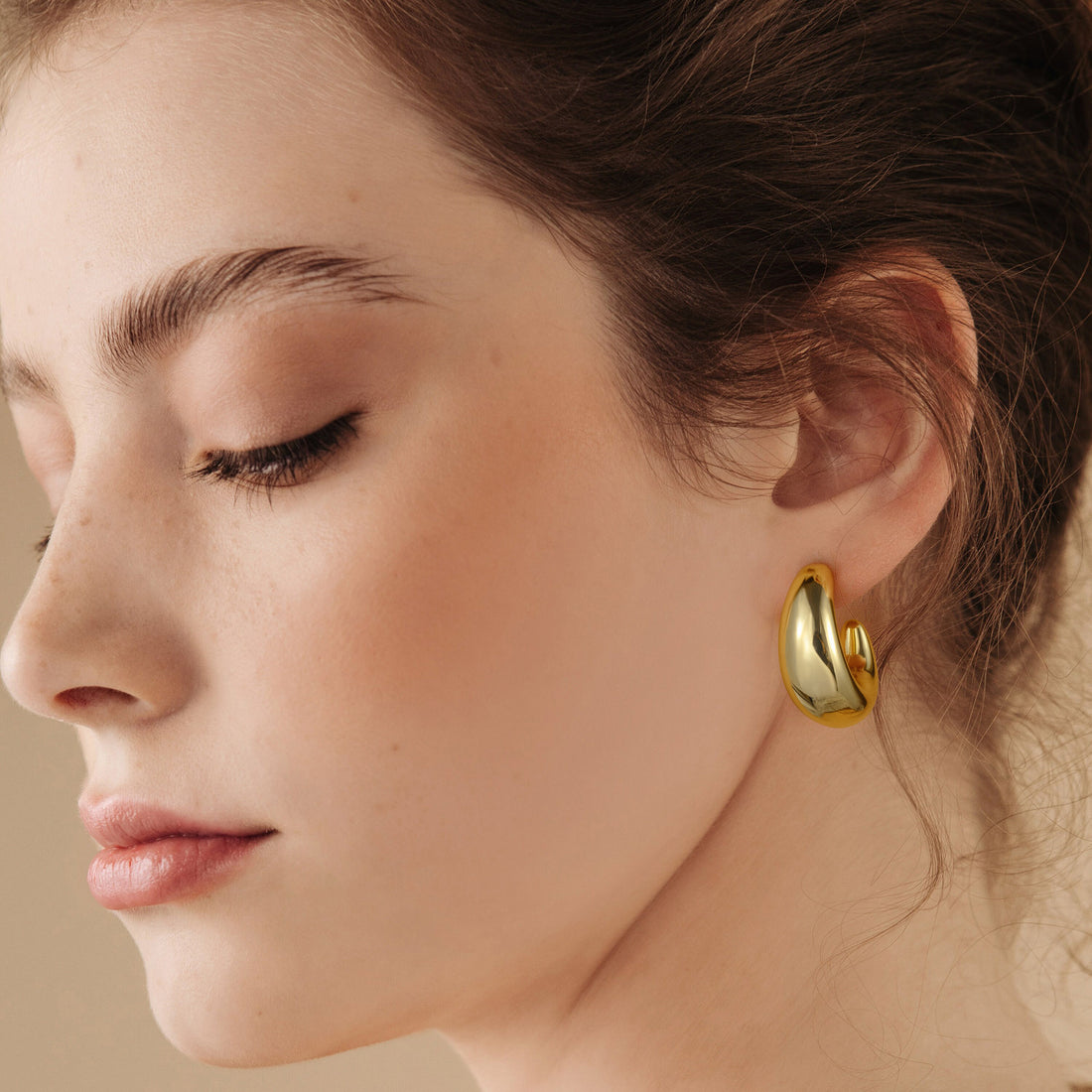 Golden/Silvery-colored, C-shaped earrings with two pointed tips and a wide middle